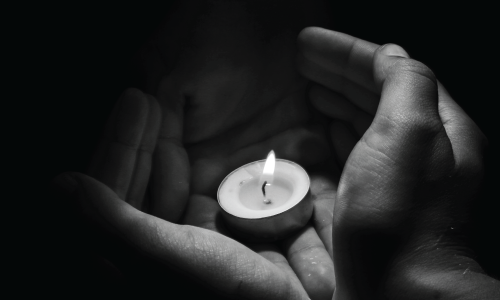 imagen en blanco y negro de manos sosteniendo una vela.