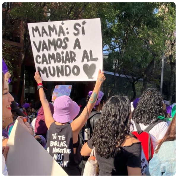 En imagen una mujer en la Marcha 8M con una pnacarta que dice: mamá si vamos a cambiar el mundo