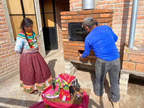 Imagen: dos personas indígenas utilizando una cocina ecológica en la comunidad de Guarijíos, en Álamos, Sonora.