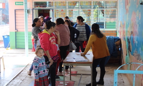 Madres de familia haciendo previo registro de sus hijas e hijos fuera del salón de clase. Programa dibujando un mañana heinz