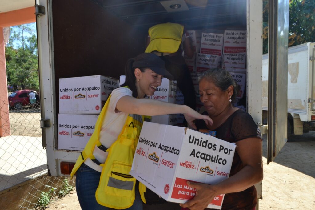 En imagen una persona voluntaria entregando una despensa a una persona afectada por el huracán Otis en Guerrero.
