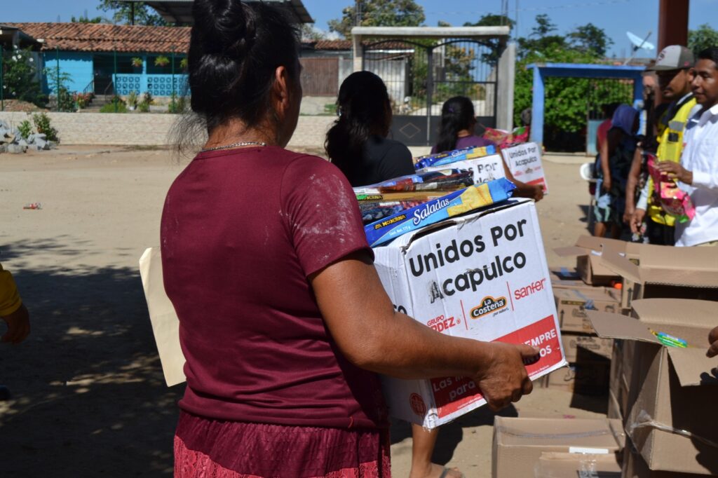 En imagen una persona afectada por el huracán Otis en Guerrero llevando una caja con víveres.